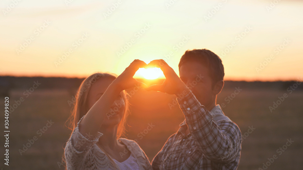 Couple making heart shape with hands. Sunset time.