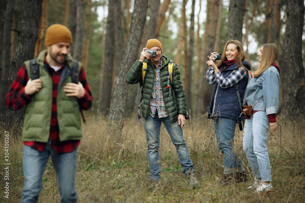 Group of friends on a camping or hiking trip in autumn day. Men and women with touristic backpacks going throught the forest, talking, laughting. Leisure activity, friendship, weekend. Group of friends on a camping or hiking trip in autumn day. Men and women with touristic backpacks going throught the forest, talking, laughting. Leisure activity, friendship, weekend.