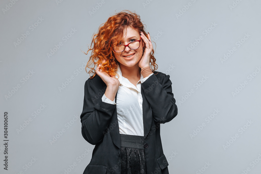 Red-haired woman in a suit and touches glasses Red-haired woman in a suit and touches glasses
