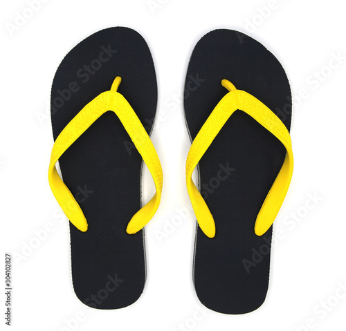 Tropical summer concept. black sandals, yellow straps from the top view on white blackground.