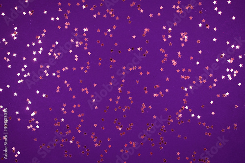 little gold stars on purple background Festive holiday background. Celebration concept. Top view,