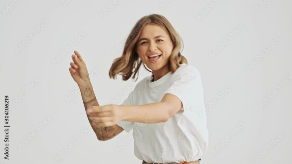 Good looking happy young woman wearing white basic t-shirt dancing isolated over white background Good looking happy young woman wearing white basic t-shirt dancing isolated over white background
