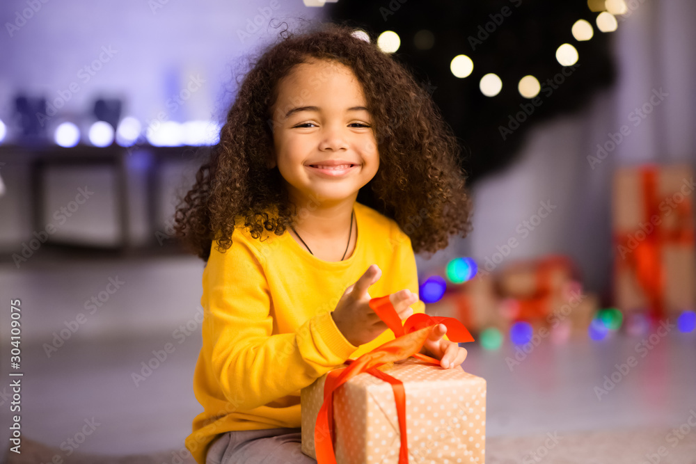 Adorable african american kid enjoying Christmas gift at home Adorable african american kid enjoying Christmas gift at home
