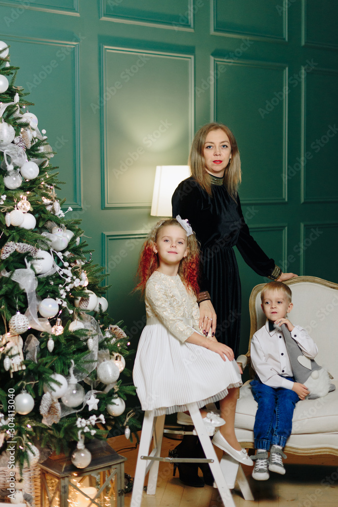 mother with two children near the Christmas tree indoors