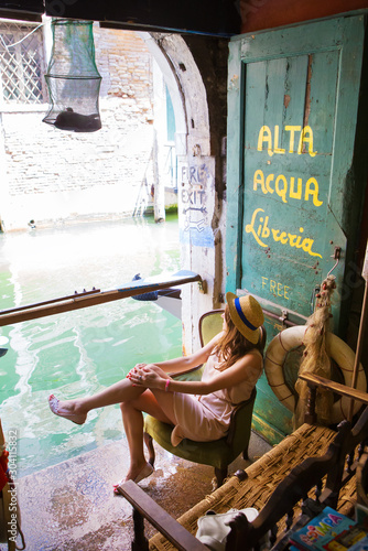 girl sits in a bookstore on the water of Alta Acqua Libreria in Venice, Italy
