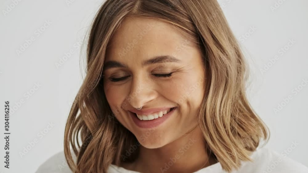Close up view of flirty smiling young woman wearing basic t-shirt with nose piercing isolated over white background Close up view of flirty smiling young woman wearing basic t-shirt with nose piercing isolated over white background