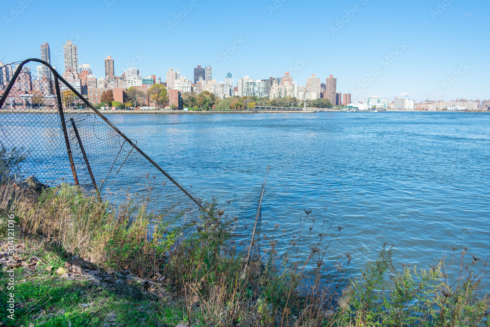 Obraz premium Shoreline of Astoria Queens New York with the East River and the Manhattan and Roosevelt Island Skyline in the background