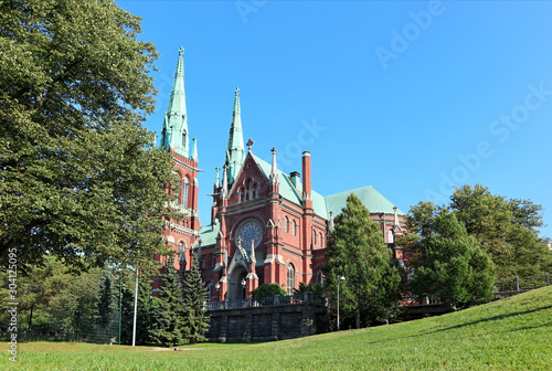 Famous gothic red church historic architecture landmark in Helsinki, Finland with blue sky and vivid green grass. City Europe travel photography photo