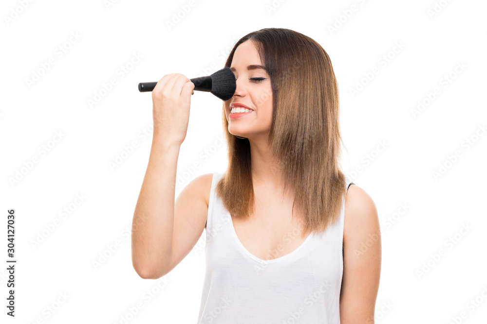 Young woman over isolated white background with makeup brush Young woman over isolated white background with makeup brush