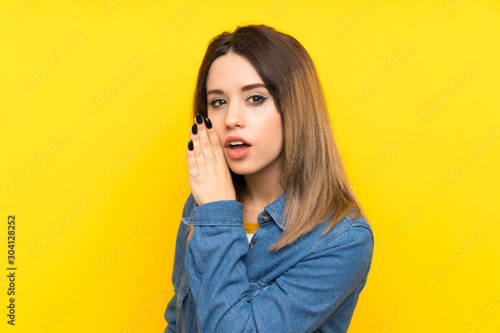 Young woman over yellow background whispering something