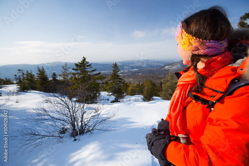 A woman takes in the dramatic vews of the Presidential Range and surrounding hills of the Mount Washington Valley while snowshoeing along Black Cap Mountain Trail near the summit of Black Cap Mountain in the Green Hills Preserve near North Conway, New Hampshire. photo