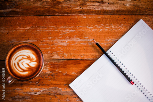 Blank notebook white screen with coffee on wooden table