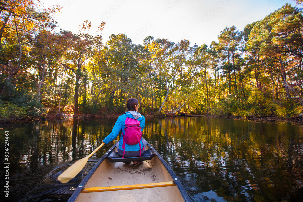 Rear view of woman canoeing in pond Rear view of woman canoeing in pond