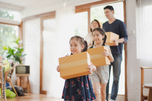 Young Asian family with daughter holds carton and walking in to a new home in moving relocation day which Excited smiling and felling happy. Mother Father and daughter move on a new home concept. © linghaa