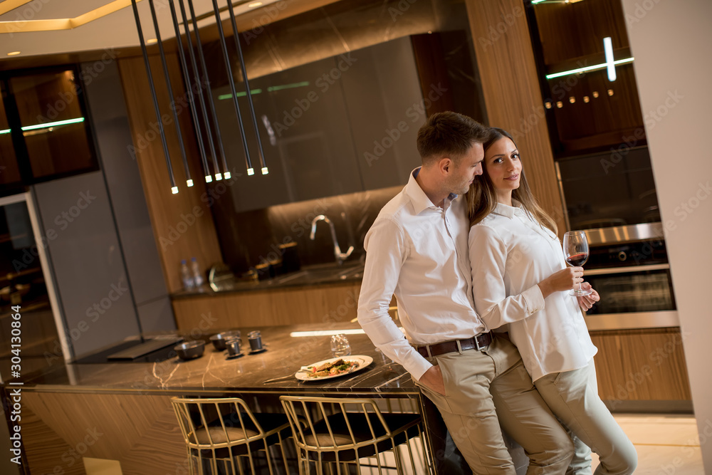 Obraz premium Sweet couple having drinking red wine after a romantic dinner at luxury kitchen