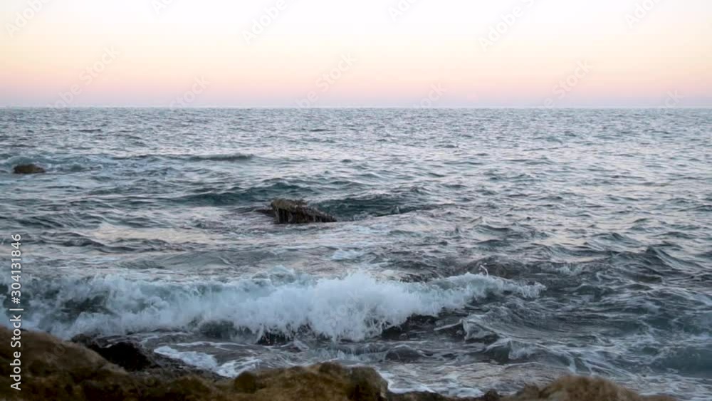 Waves on the Mediterranean Sea. Waves hit the rocks at pink sunset. Slow motion Waves on the Mediterranean Sea. Waves hit the rocks at pink sunset. Slow motion