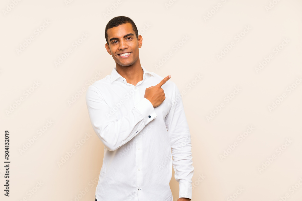 Young handsome brunette man over isolated background pointing to the side to present a product Young handsome brunette man over isolated background pointing to the side to present a product
