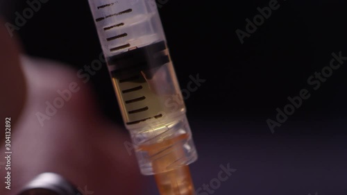 Close-up of brown liquid heroin getting sucked up into a syringe from a needle