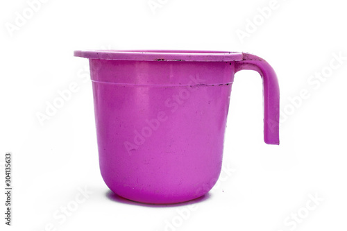 Close up shot of pink-colored plastic bathroom mug isolated on pink colored glossy background.