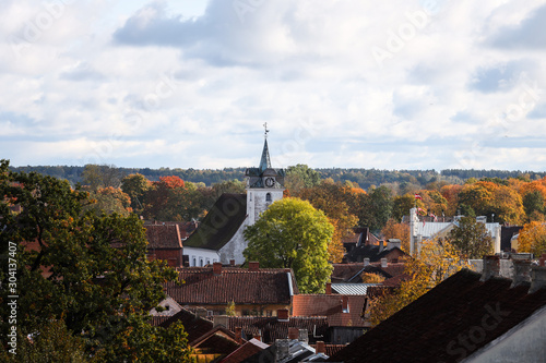 Small countryside city rooftop view of old white church as main subject. Photo taken in Latvia-Kuldīga on a sunny autumn day.