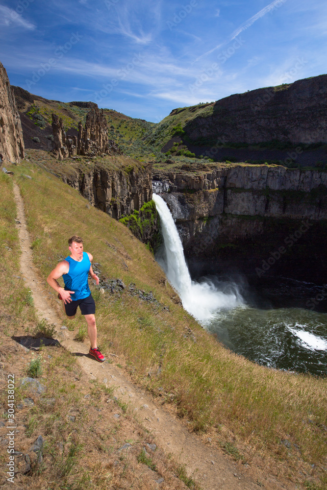 Fitness trainer goes for an exposed trail run around the rim of the Palouse Falls in southeastern Washington State. The short-but-scenic trail drops down from the main parking area and runs along the Palouse River, falls and surrounding ampitheater. Fitness trainer goes for an exposed trail run around the rim of the Palouse Falls in southeastern Washington State. The short-but-scenic trail drops down from the main parking area and runs along the Palouse River, falls and surrounding ampitheater.