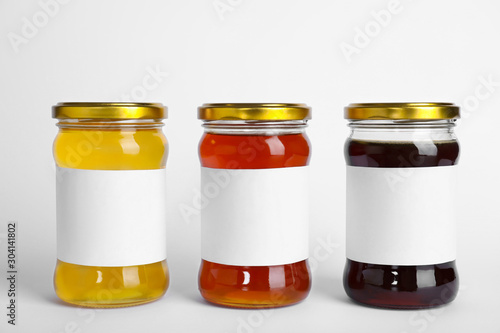 Different types of honey with blank labels isolated on white