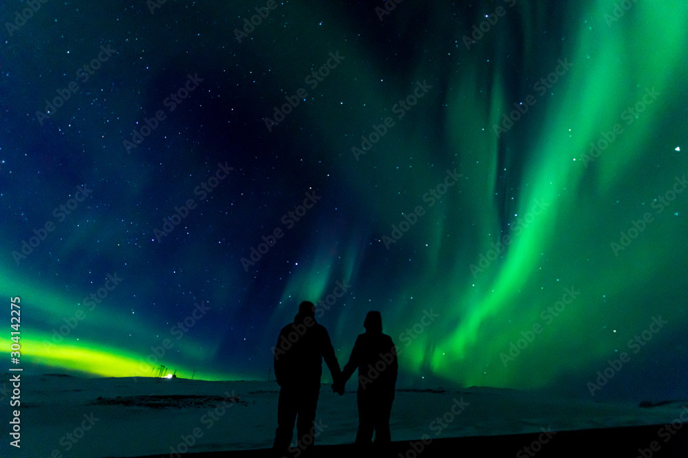 A silhouette of a couple with the northern lights in the background, in Iceland.