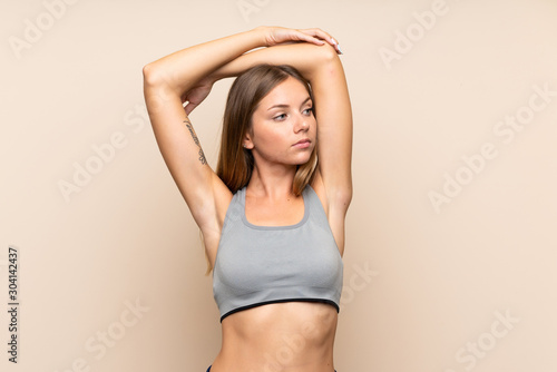 Young blonde sport girl over isolated background stretching