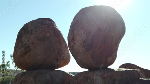 Australia, Northern Territory. Aboriginal land in Red Centre. Sunbeams sky at sunset behind iconic the Eggs of mythical Rainbow Serpent at Karlu Karlu - Devils Marbles Conservation Reserve. photo