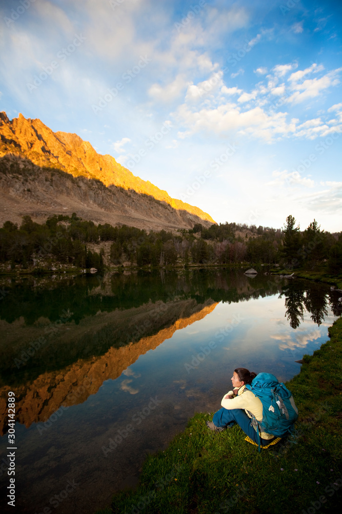 A woman pauses to take in the view at sunset on Upper Chamberlain Lake in the White Cloud Moutains in Idaho. A woman pauses to take in the view at sunset on Upper Chamberlain Lake in the White Cloud Moutains in Idaho.
