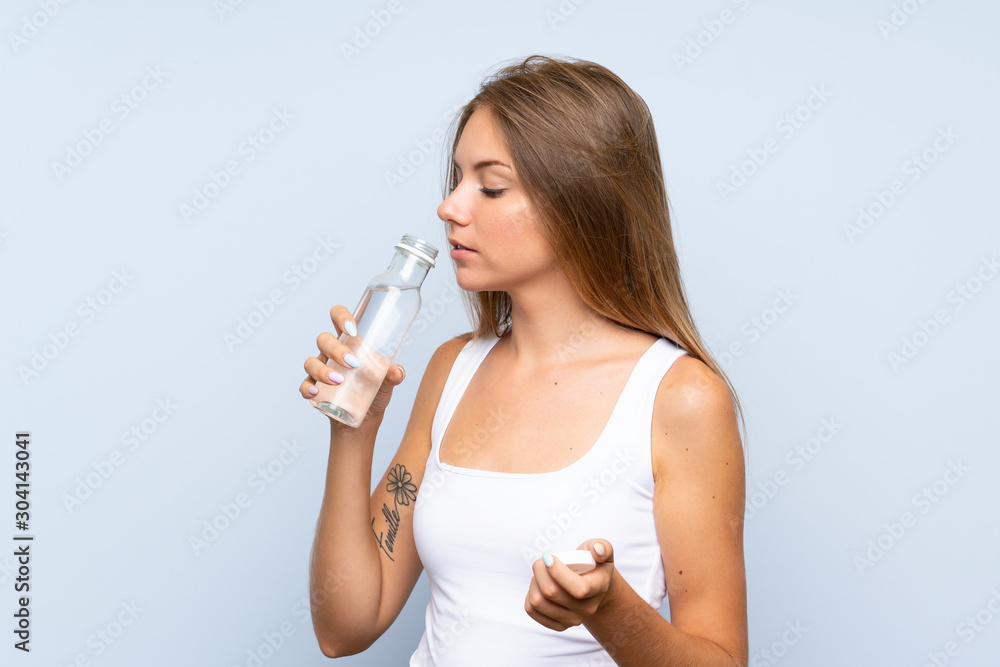 Young blonde girl with a bottle of water over isolated background Young blonde girl with a bottle of water over isolated background