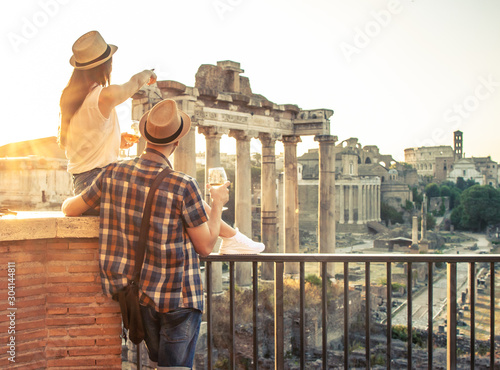 Photography Young couple tourist with glass of white wine at Roman Forum at sunrise