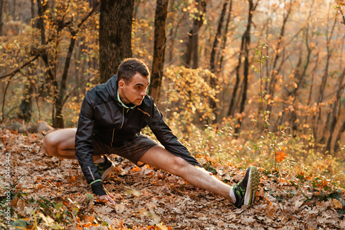 Concept of sport and active lifestyle. A young man is engaged in warm-up, fitness in the autumn forest