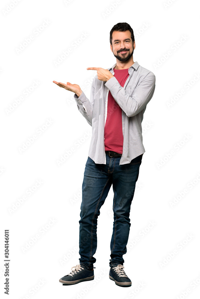 Full-length shot of Handsome man with beard holding copyspace imaginary on the palm to insert an ad over isolated white background Full-length shot of Handsome man with beard holding copyspace imaginary on the palm to insert an ad over isolated white background