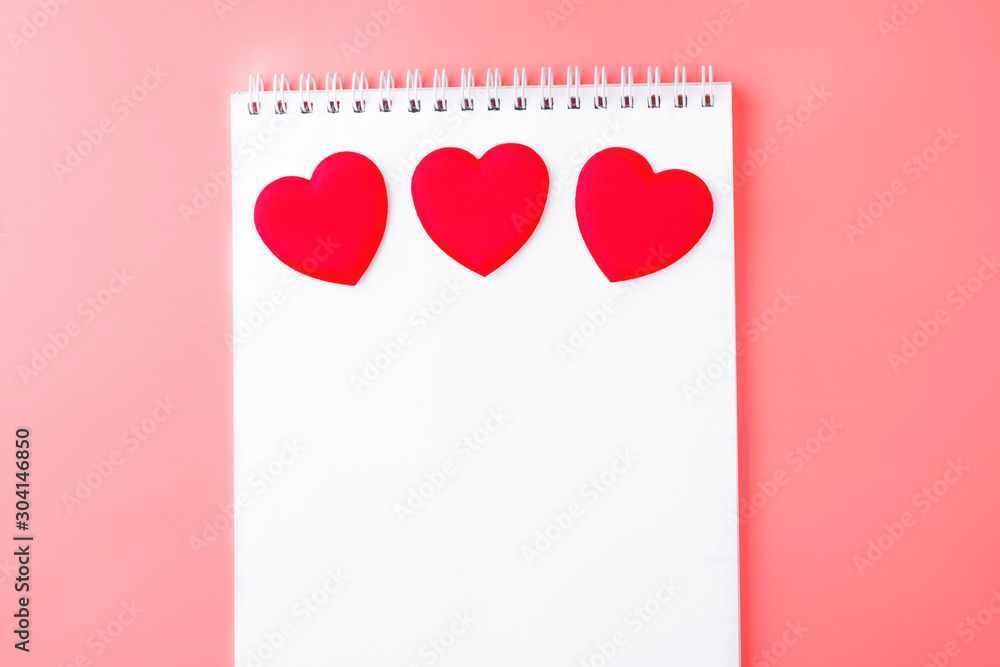 Valentines day background. Оpen blank notebook and red hearts on a pink peach background. Writing romantic letters. Top view. Copy space - obrazy, fototapety, plakaty 