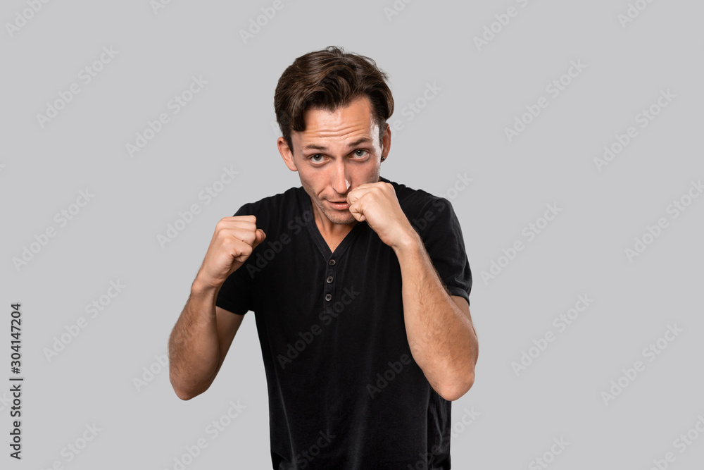 Man ready to fight standing in a boxing pose isolated over grey background. Defending oneself Man ready to fight standing in a boxing pose isolated over grey background. Defending oneself