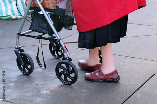 Elderly lady walking with walking aid shopping frame