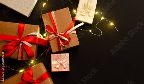 Gift or present box with red and whight bow ribbon and on garland on a black backgroundwooden photo