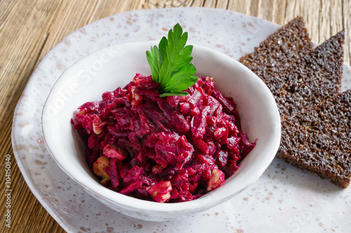 beetroot, walnuts, and garlic salad dressed with mayonnaise, decorated with parsley, and served with fried rye bread on a plate