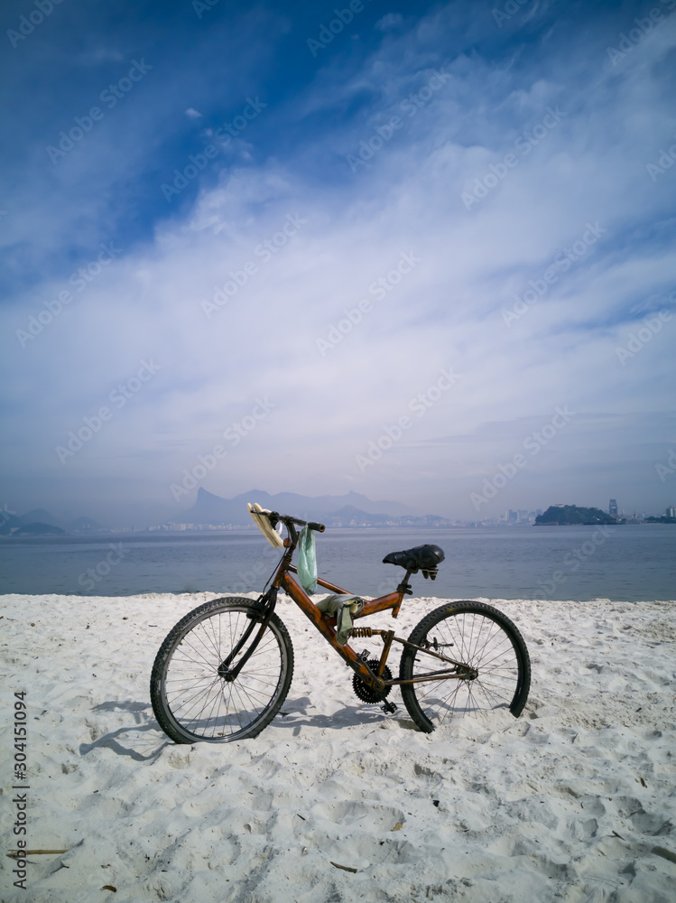 Ecological transport, ecological transport, bicycle parked in the sand, between building and sea, in Icarai beach, Niteroi, Rio de Janeiro, Brazil.