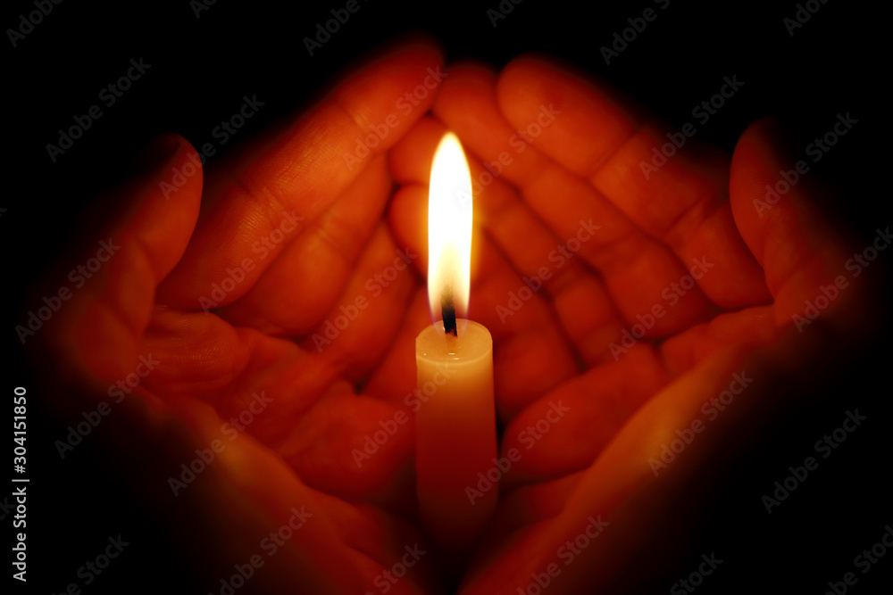 Two hands around a burning candle Two hands around a burning candle