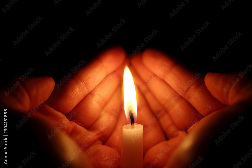 Two hands around a burning candle Two hands around a burning candle