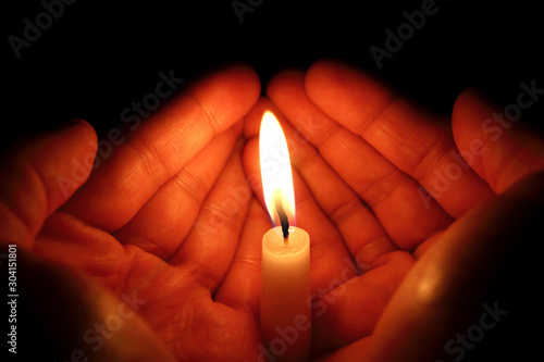 Two hands around a burning candle
