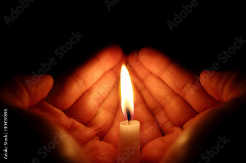 Two hands around a burning candle photo
