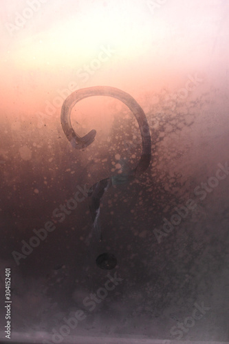 A drawn question mark on a foggy, foggy window.