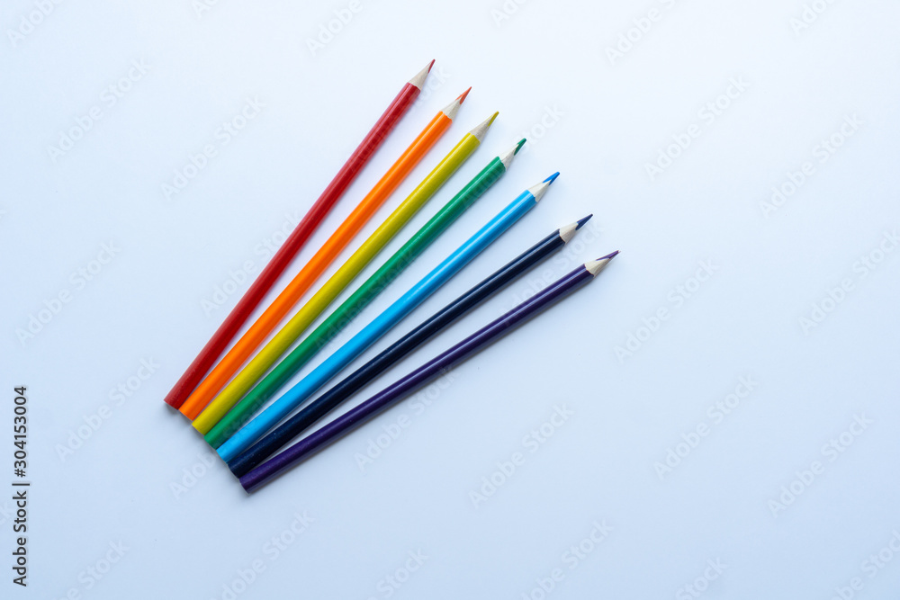 Set of seven sharp rainbow-colored pencils from top view on a white background. Concept of creativity. Art supplies. Minimalism. Childhood.