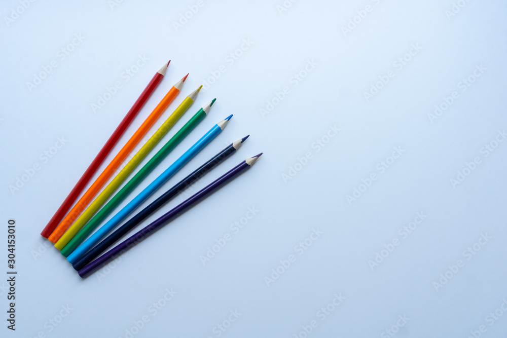 Set of seven sharp rainbow-colored pencils from top view on a white background. Concept of creativity. Art supplies. Minimalism. Childhood. Space for text. Set of seven sharp rainbow-colored pencils from top view on a white background. Concept of creativity. Art supplies. Minimalism. Childhood. Space for text.