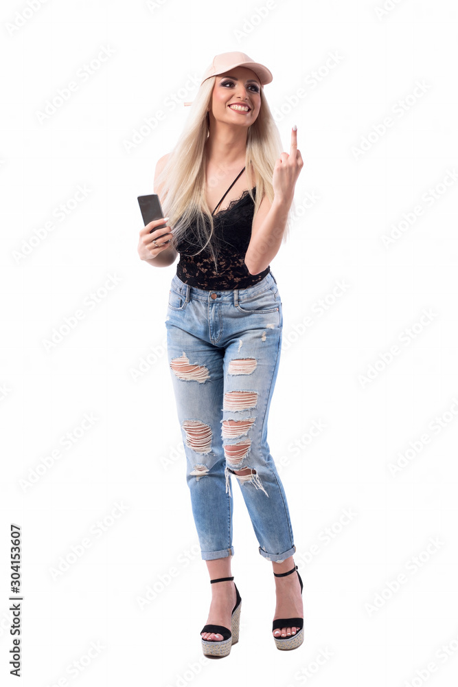 Mad young laughing blonde woman holding cellphone looking away and showing middle finger rude hand symbol. Full body isolated on white background. Mad young laughing blonde woman holding cellphone looking away and showing middle finger rude hand symbol. Full body isolated on white background.