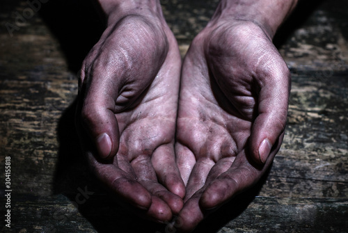 Male dirty worker hands asking for palms on dirty wooden background. The concept of assistance, begging, poverty. Share hope