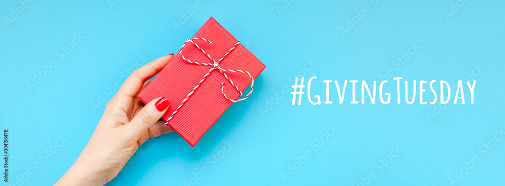 Giving Tuesday concept with red gift box in hand - obrazy, fototapety, plakaty 